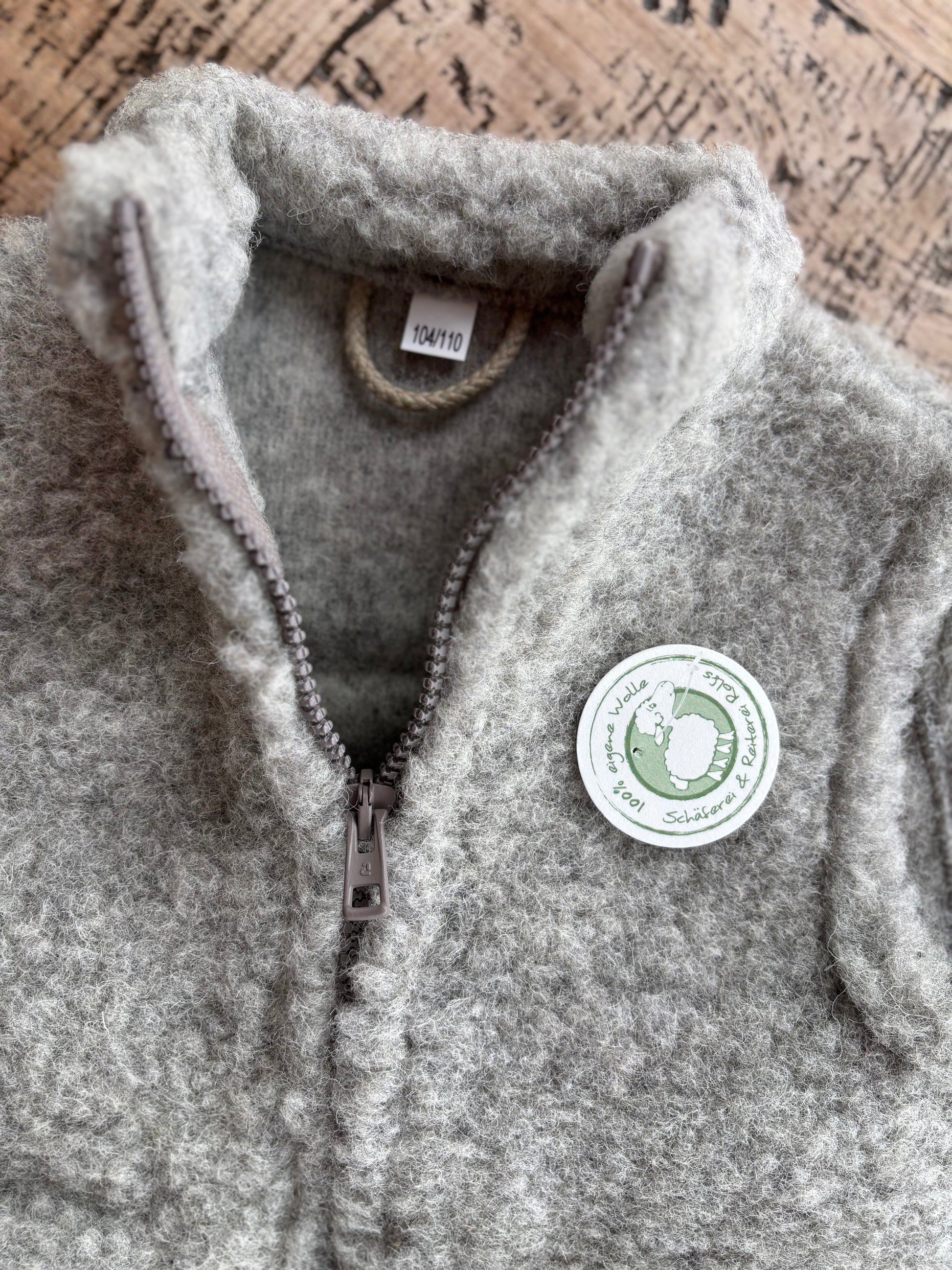 Detailaufnahme der grauen Kinderweste aus Schurwolle – fein verarbeitete Nähte und natürliche Wollstruktur, hergestellt in Deutschland bei der Schäferei Rolfs an der Nordsee. Nachhaltig, warm und robust – ideal für aktive Kinder.

