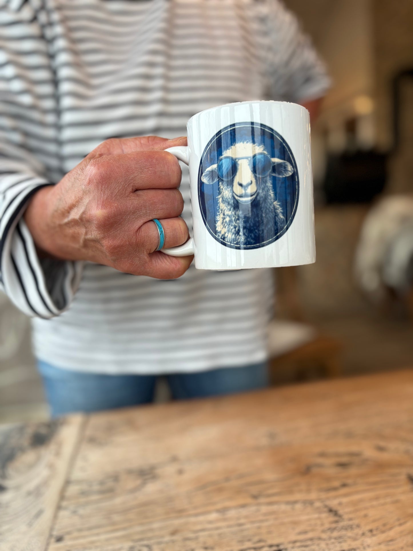 Weißer Porzellanbecher mit blauem Schafmotiv aus der DeichHeld-Kollektion der Schäferei Rolfs an der Nordsee – perfekt für Fans der Schäferei und echte Deichhelden.