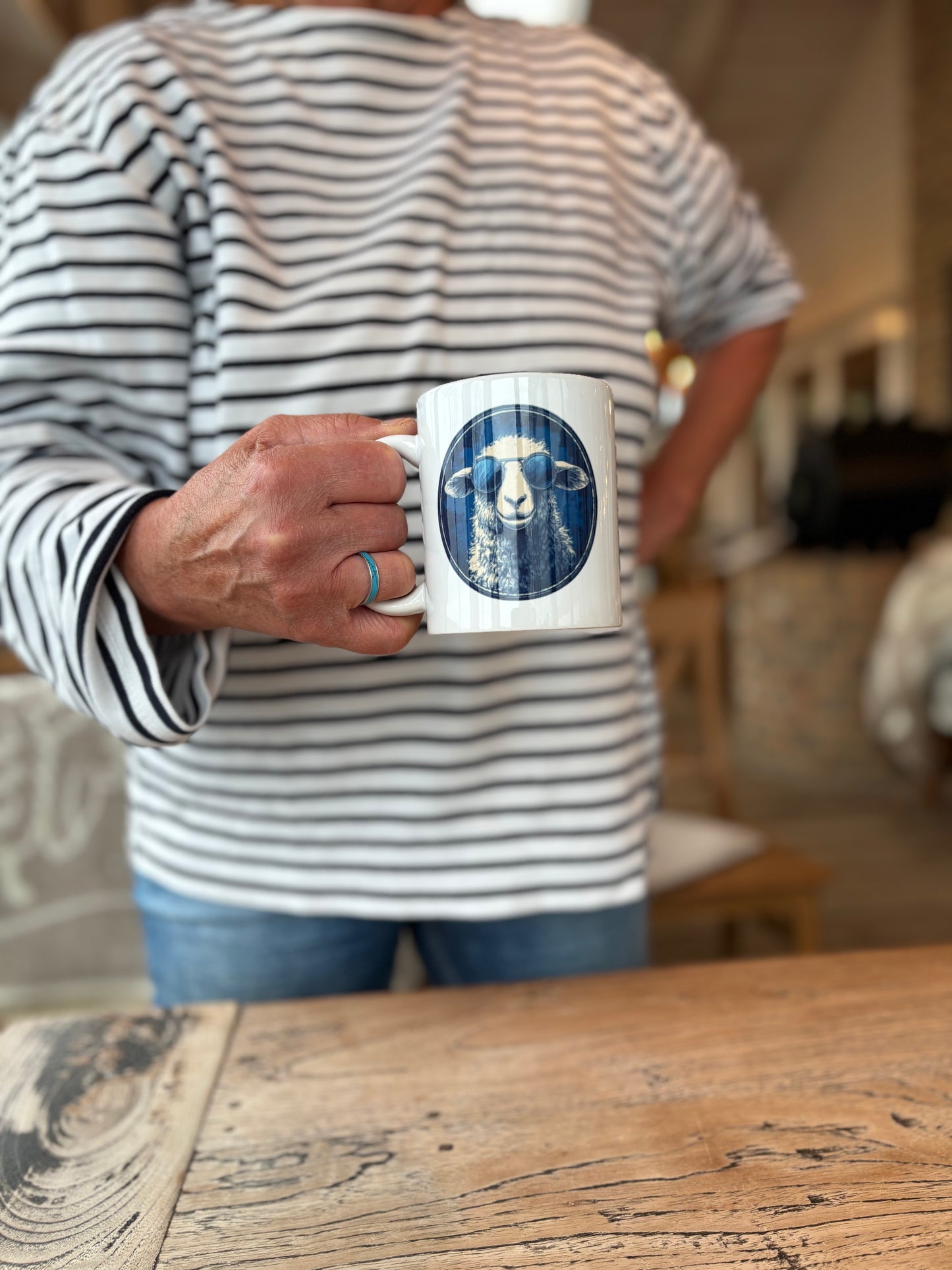 Weißer Porzellanbecher mit blauem Schafmotiv aus der DeichHeld-Kollektion der Schäferei Rolfs an der Nordsee – perfekt für Fans der Schäferei und echte Deichhelden.