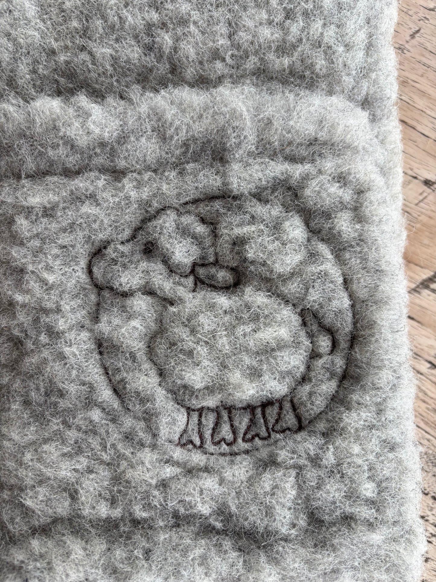 Logo der Schäferei Rolfs auf einer Kinderweste aus Schurwolle – das gestickte Schäfchen steht für Handwerksqualität, Nachhaltigkeit und echte Deichschaf-Wolle von der Nordsee.