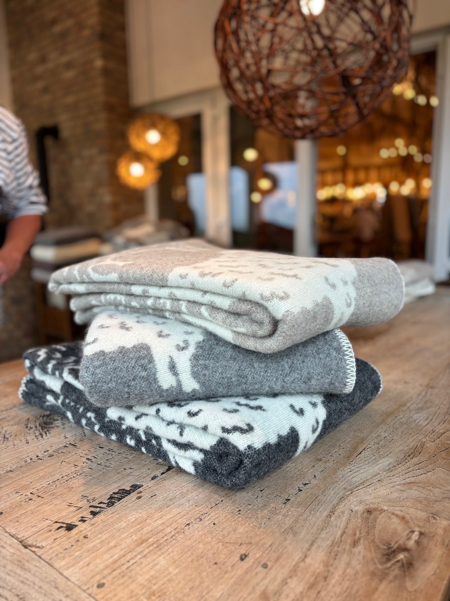 Wolldecken aus Schurwolle in Beige, Anthrazit und Grau mit liebevollem Schafmotiv – weich und aus natürlichen Materialien gefertigt. Ideal für Schafliebhaber und umweltbewusste Käufer, die Wärme, Gemütlichkeit und  Handwerkskunst schätzen.