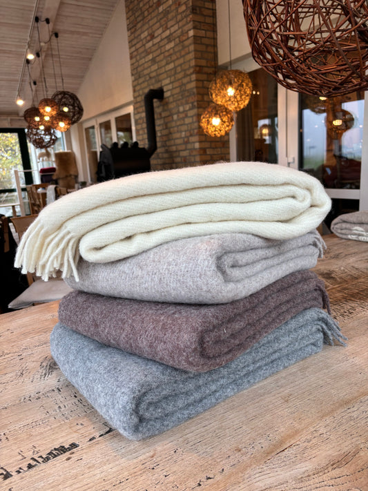 Wolldecke aus 100 % Schafwolle in natürlichen Uni-Farben – schlicht, nordisch und wunderbar warm. Die nachhaltige Decke von der Schäferei Rolfs ist atmungsaktiv, kuschelig und ideal für gemütliche Abende auf dem Sofa oder im Energiesparmodus nach einem langen Tag.